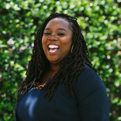 black woman outside smiling wearing blue shirt